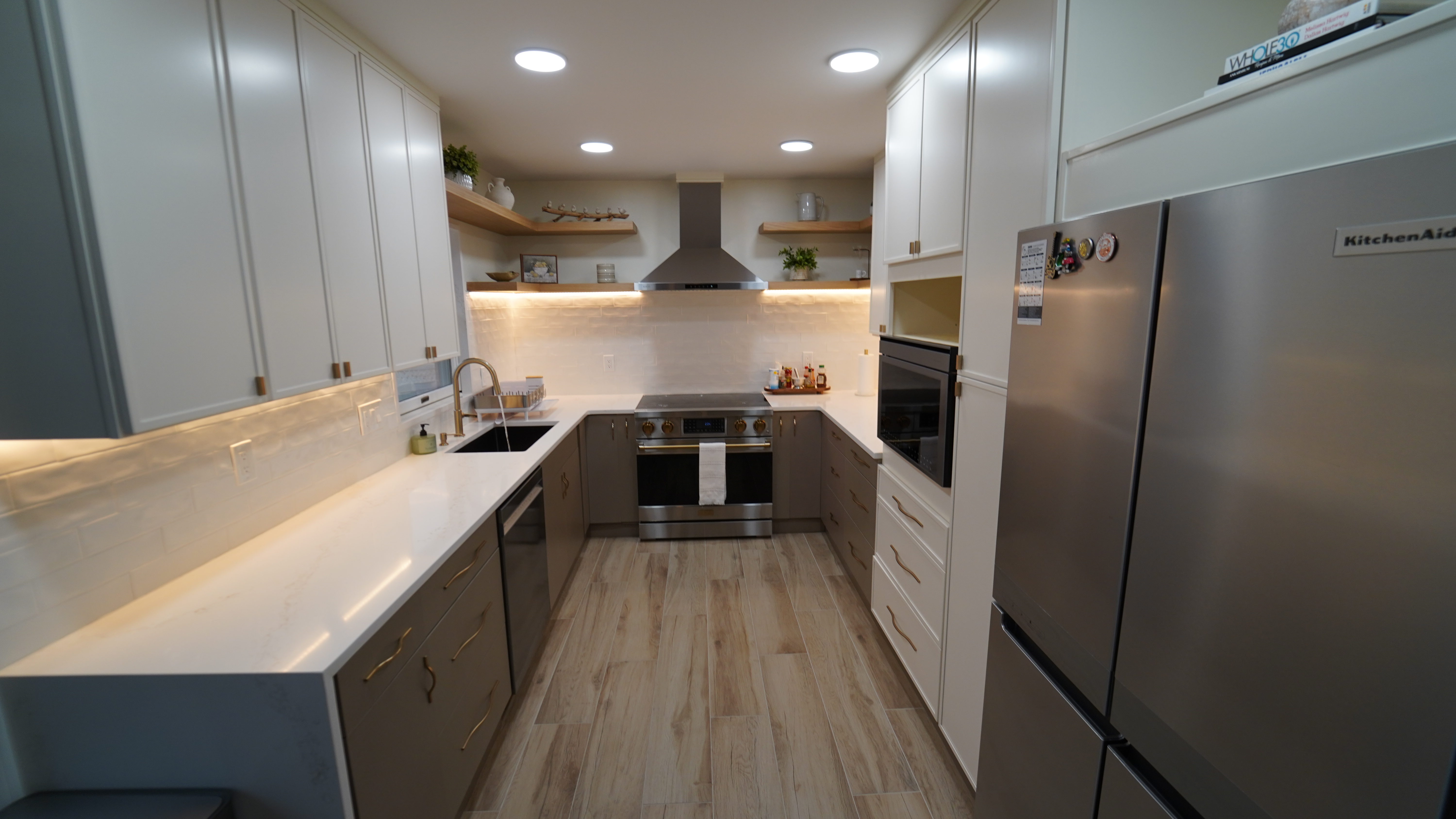 Saugus MA kitchen with two-tone cabinetry, open shelving, range, and refrigerator wall